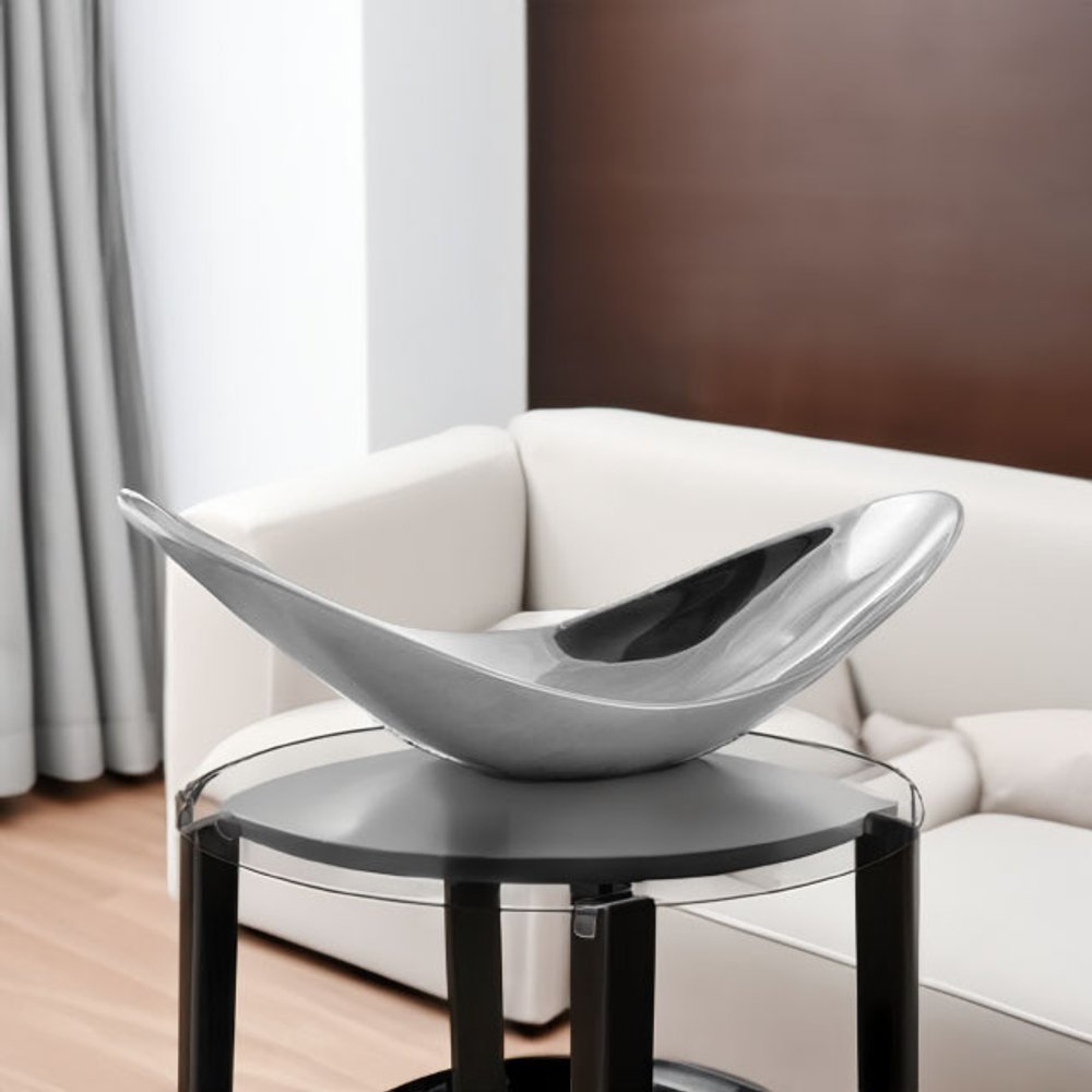20" Silver Aluminum Contemporary Scoop Decorative Bowl styled in a furnished interior with a brown wall on a tiled floor.