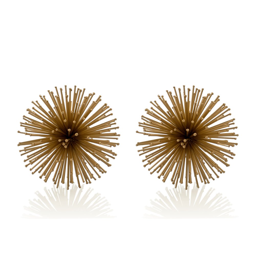 Two gold iron spiky sphere tabletop sculptures on a white background with reflections.