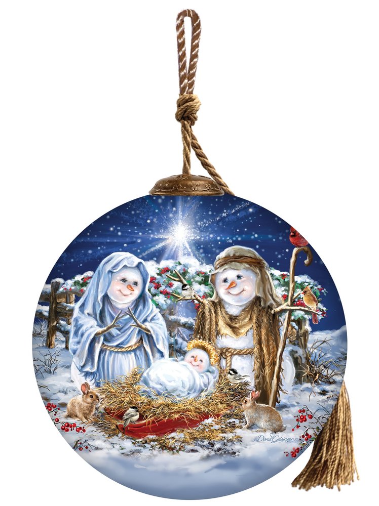 Round glass Christmas ornament depicting a snowman nativity scene with Mary, Joseph, and baby Jesus in a manger, with a starry blue background.