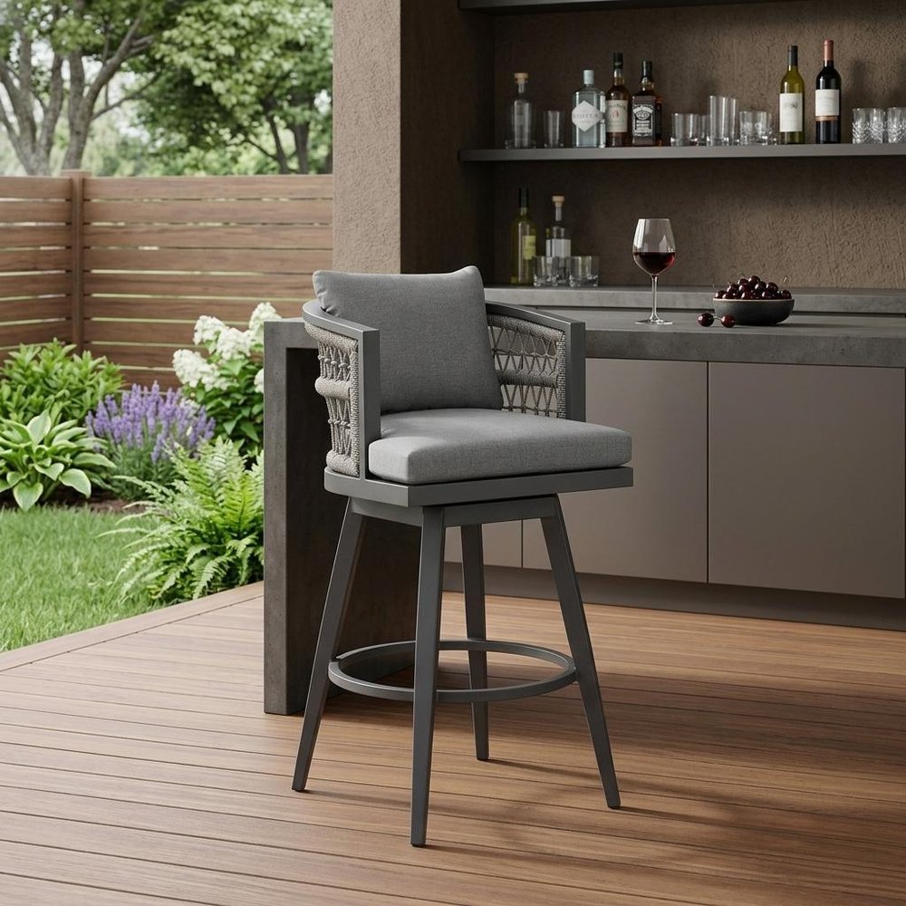 37" Gray Metal Swivel Outdoor Counter Height Bar chair with Footrest shown outdoors on a patio with greenery.