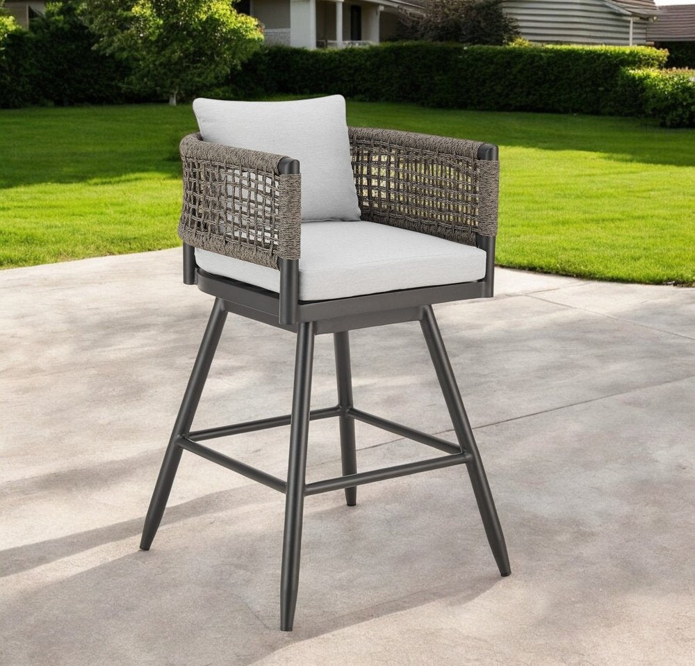 30" Black and Light Gray Aluminum Swivel Rope Back Outdoor Bar Height Chair with Footrest shown outdoors on a tiled patio with greenery.