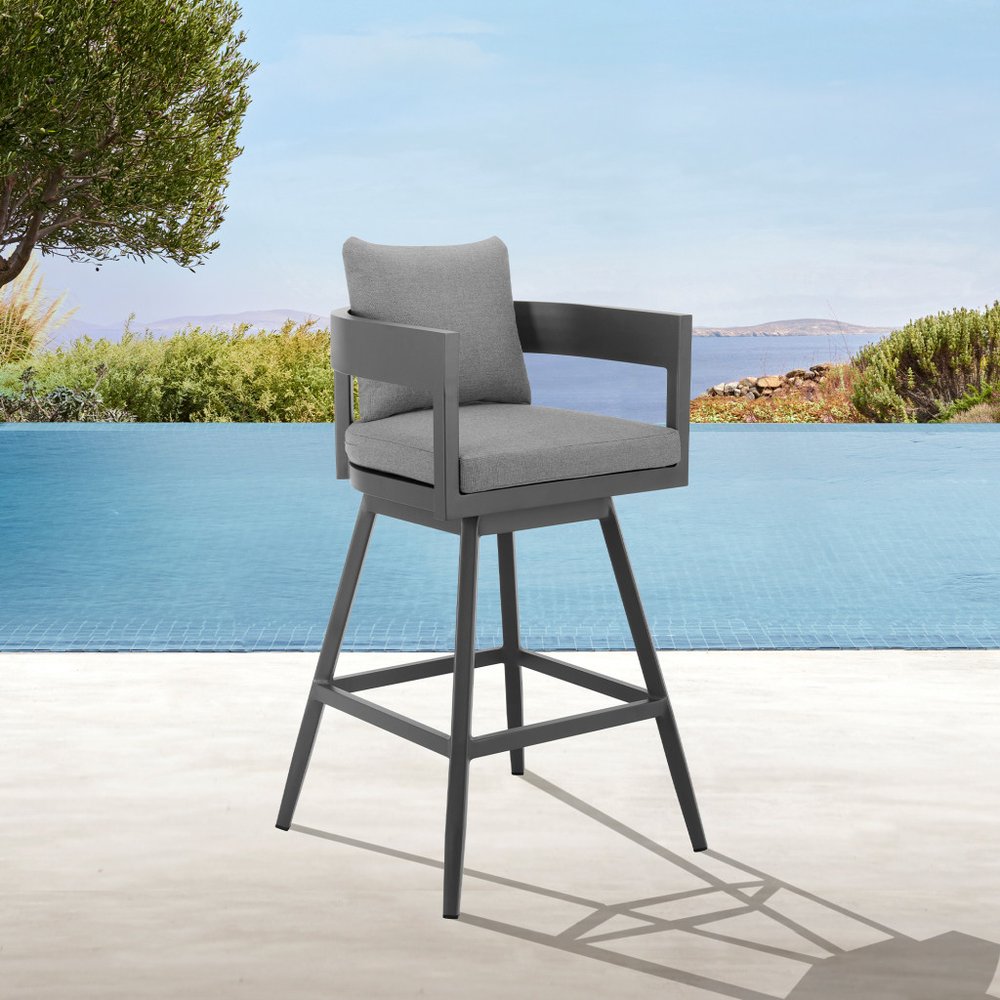 34" Dark Gray Metal Swivel Low back Outdoor Counter Height Bar chair with Footrest shown outdoors on a tiled patio.