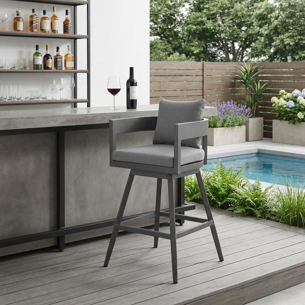 39" Dark Gray Metal Swivel Low back Outdoor Bar Height chair with Footrest shown outdoors on a tiled patio with greenery in charcoal metal.
