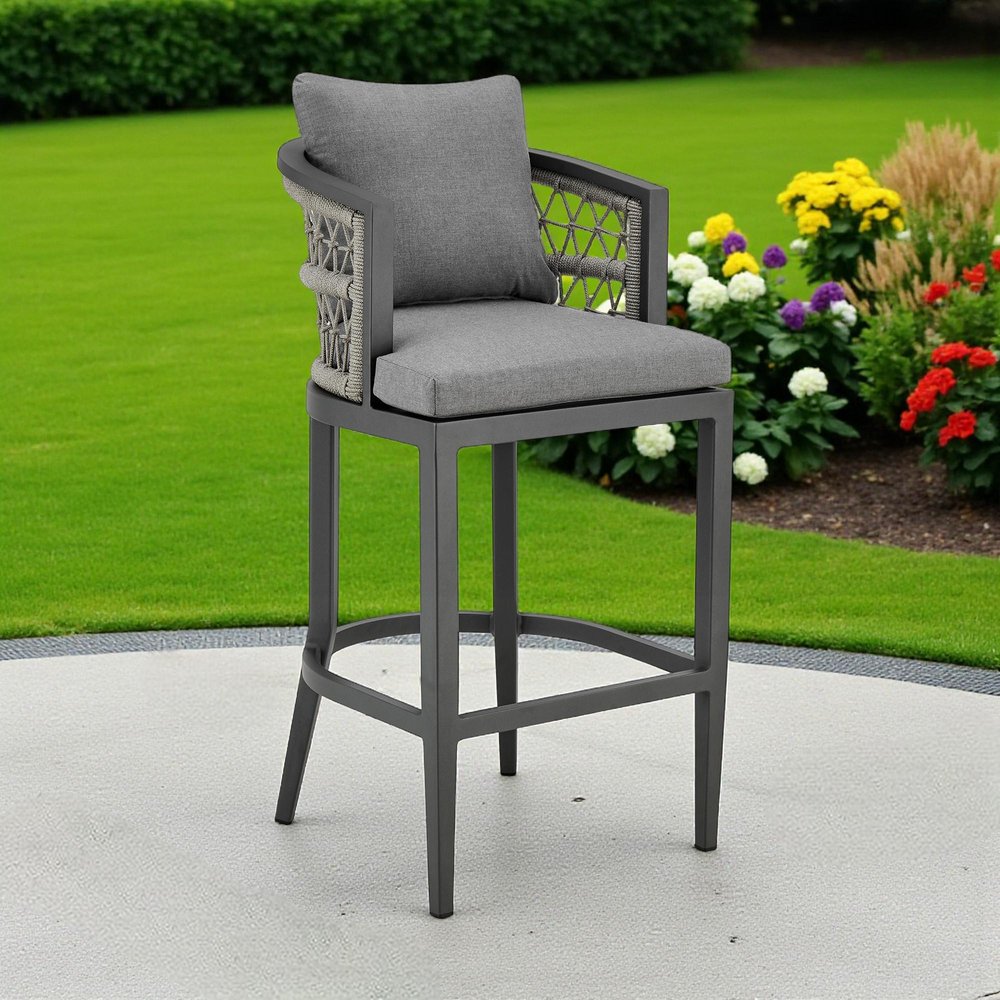 40" Gray Metal Outdoor Bar Height chair with Footrest shown outdoors on a tiled patio with greenery.