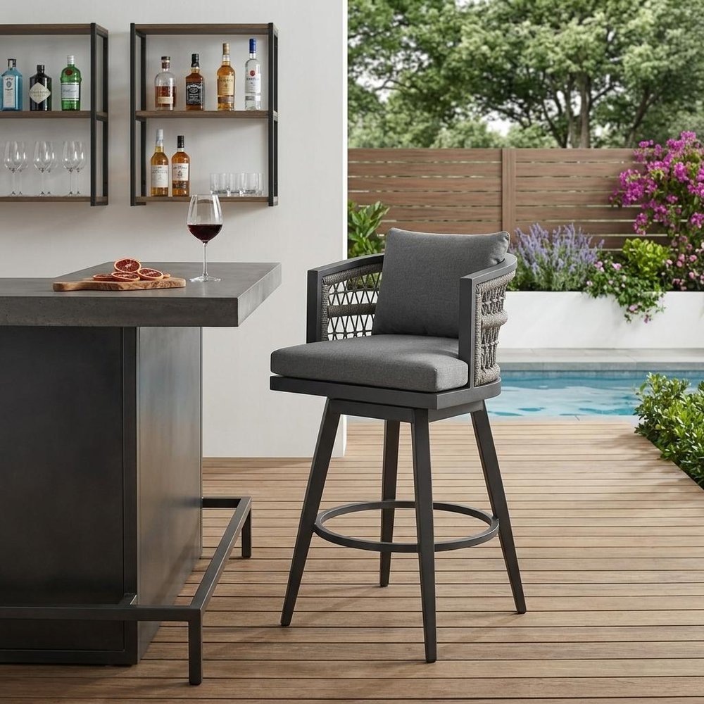 40" Gray Metal Swivel Outdoor Bar Height chair with Footrest shown outdoors on a patio with greenery.