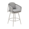 Light gray metal swivel outdoor bar chair with woven gray seat and back cushions and a footrest on a white background.