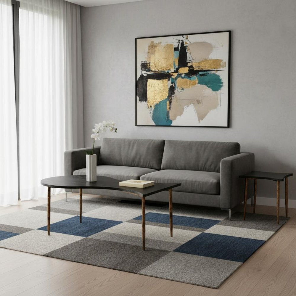 Black and bronze free-form coffee and end tables with wood and steel construction in a modern living room with gray sofa and abstract art.
