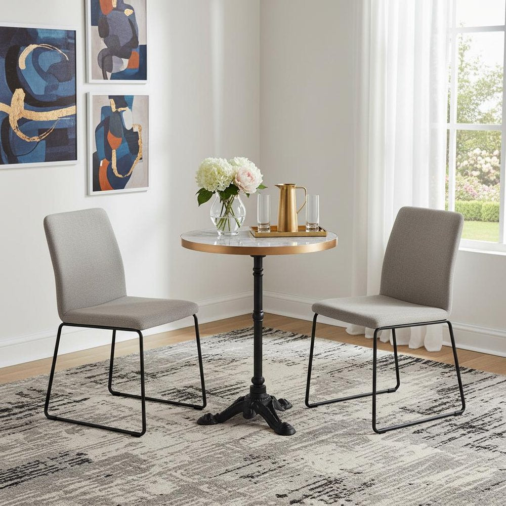 24" White And Black Wood And Aluminum Indoor Outdoor Pedestal Base Round Top Dining Table styled in a furnished interior with a light gray wall on a tiled floor.