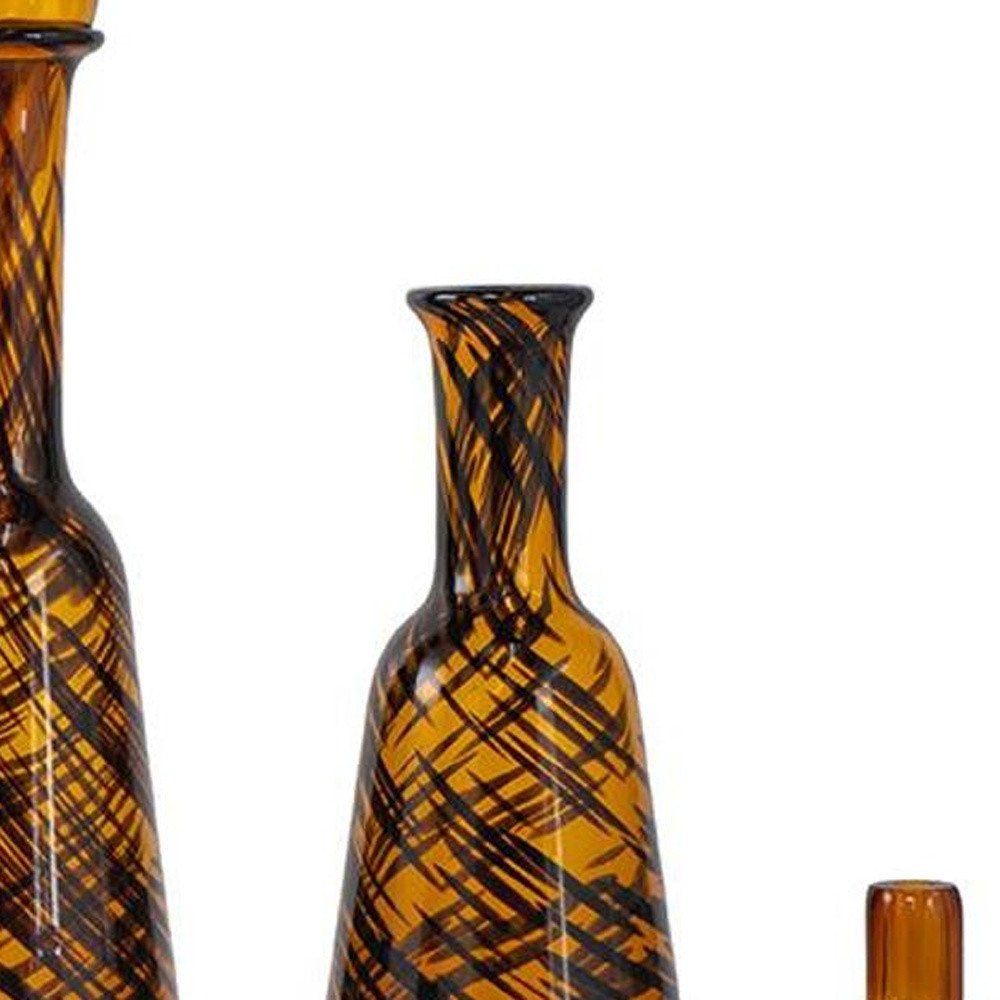 Set of Three Amber Abstract Swirl Glass Decorative Bottles With Stoppers on a white background