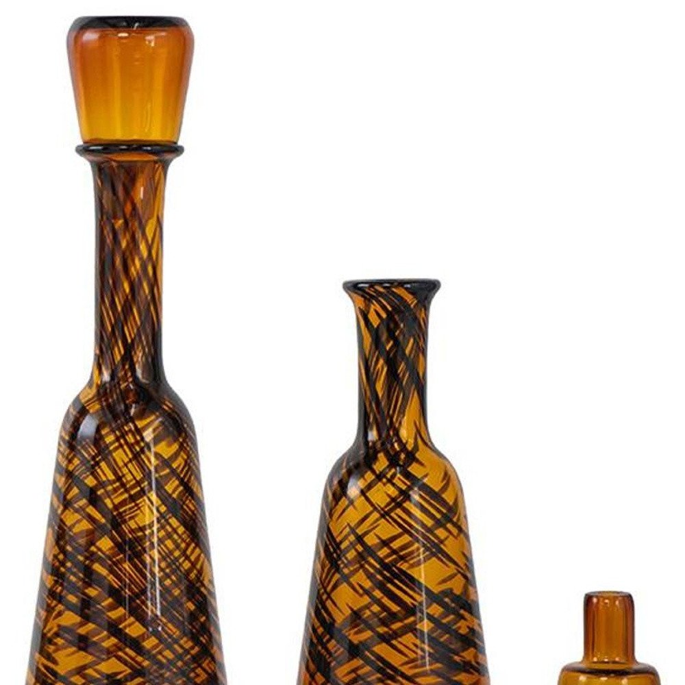 Set of Three Amber Abstract Swirl Glass Decorative Bottles With Stoppers on a white background