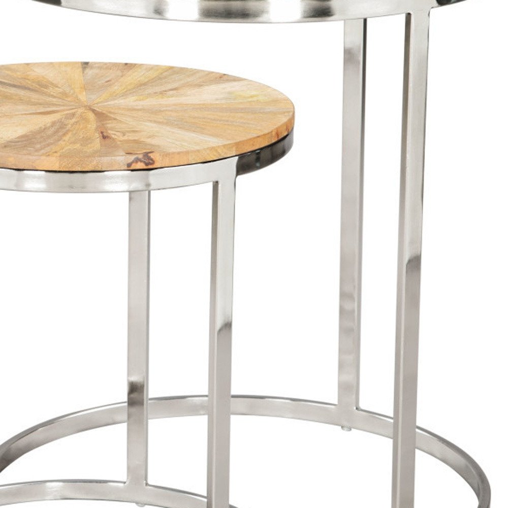 Close-up of a set of two nested round tables with natural wood tops and silver iron frames on a white background.