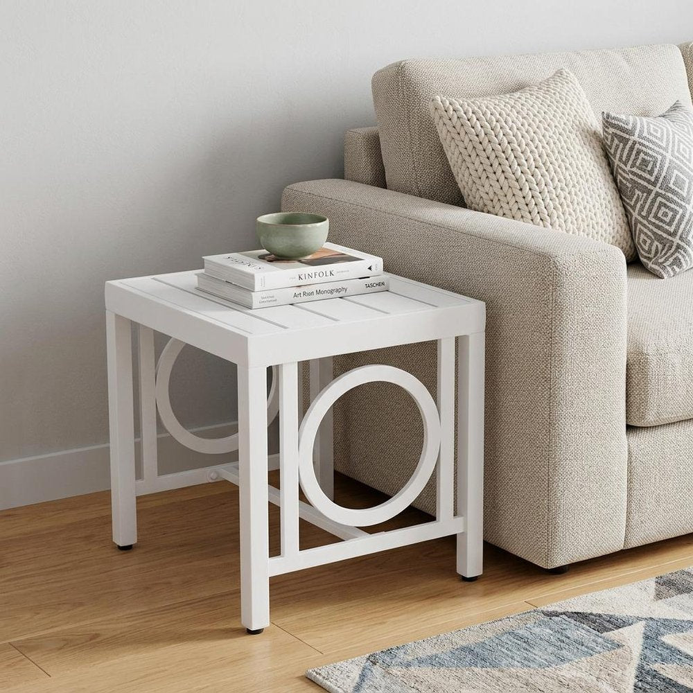 16" White Metal Outdoor Side Table styled in a furnished interior with an off-white wall on a wood floor.