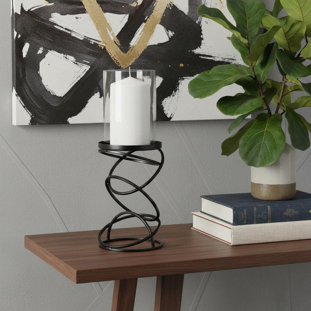 14" Black Geometric Glass And Metal Tabletop Pillar Candle Holder displayed on a tabletop in a furnished interior against a dark wall.
