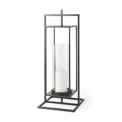 Black geometric metal lantern with glass cylinder and white candle on white background.
