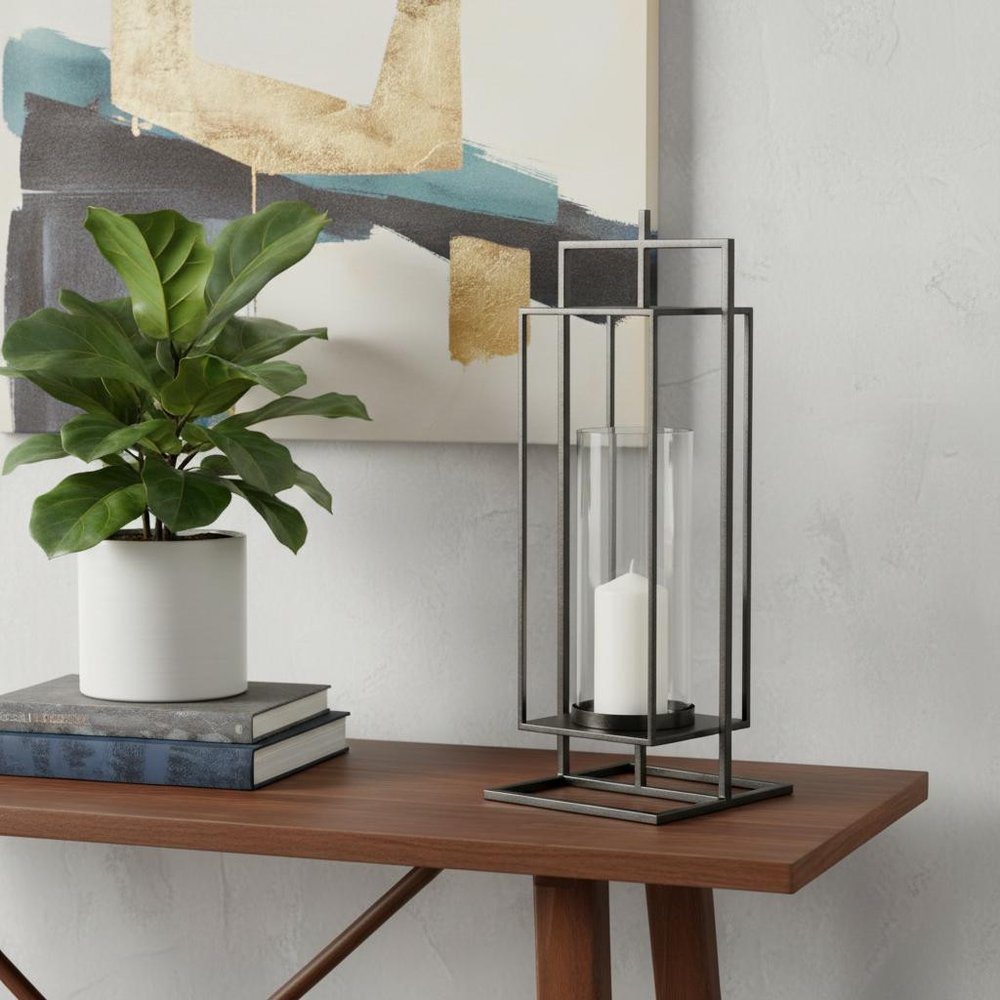 24" Black Geometric Metal Tabletop Lantern Candle Holder displayed on a tabletop in a furnished interior against an off-white wall.