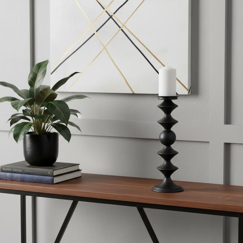 16" Black Metal Tabletop Pillar Candle Holder displayed on a tabletop in a furnished interior against an off-white wall.