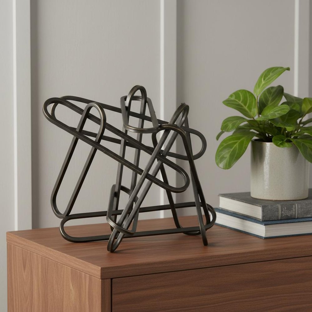 12" Black Metal Abstract Tabletop Sculpture styled in a furnished interior with a light gray wall on a dark wood floor.