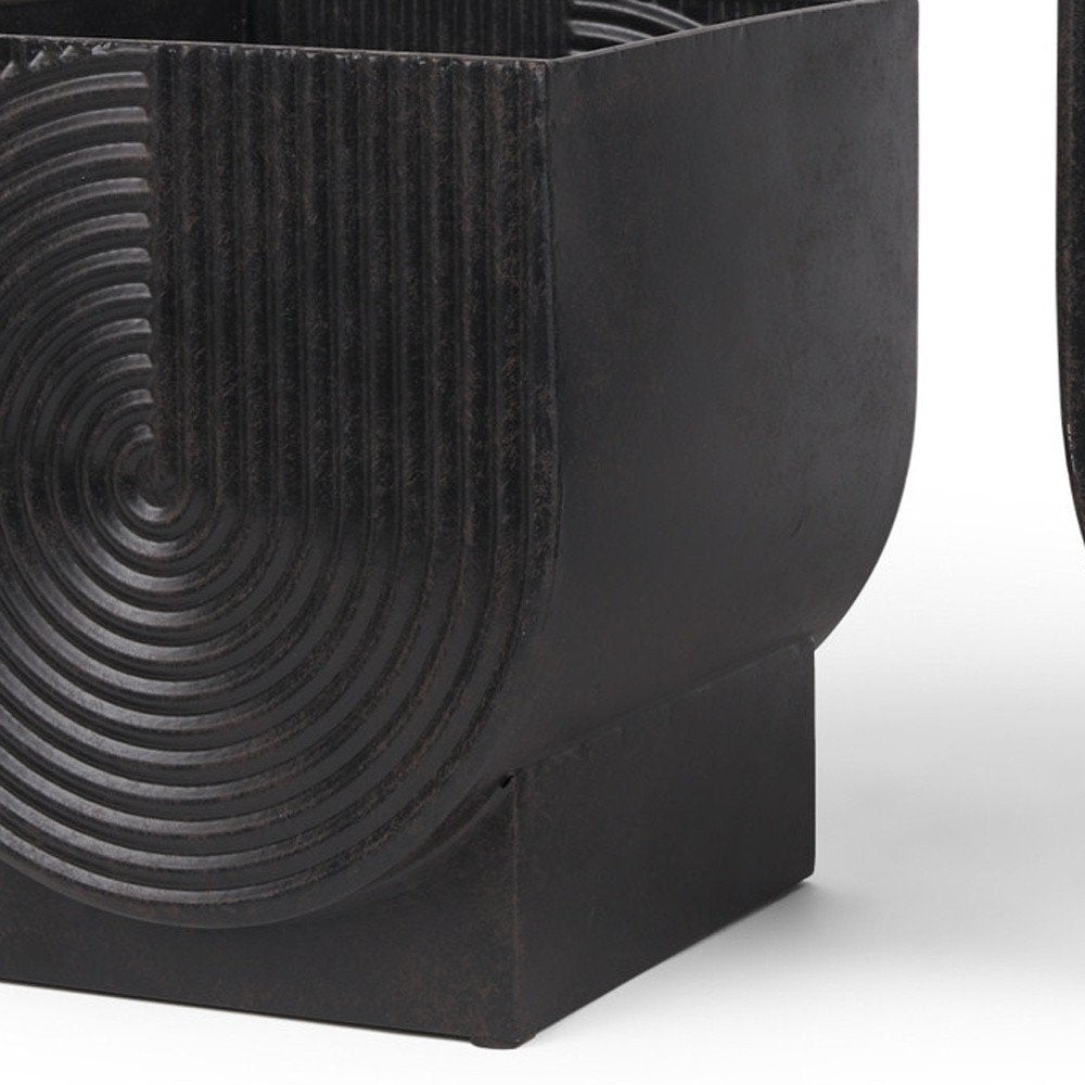 Close-up of a black metal planter with a ribbed spiral design on a white background.