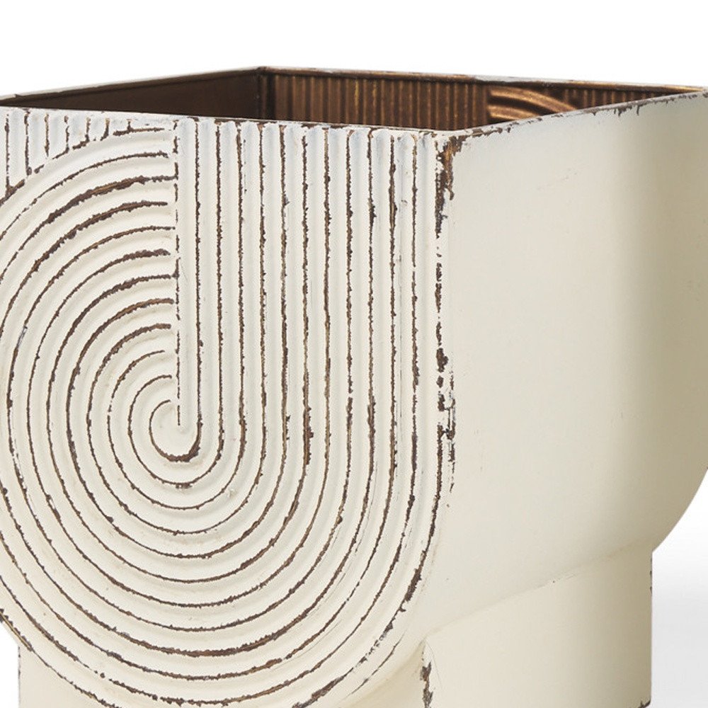 Close-up of a white metal planter with a distressed finish and a ribbed, concentric circle design on the side.