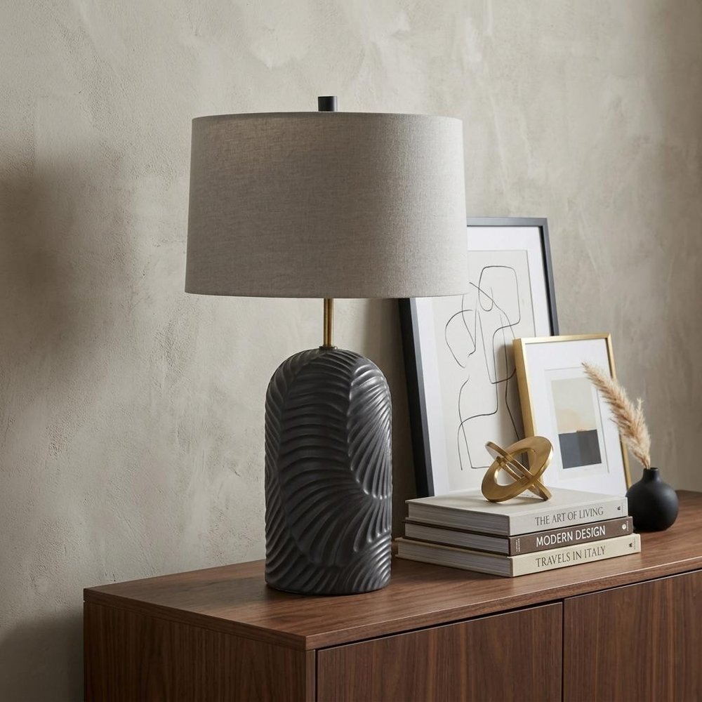 29" Navy Blue Round Bedside Lamp With Drum Shade styled in a furnished interior with a light gray wall on a dark wood floor.