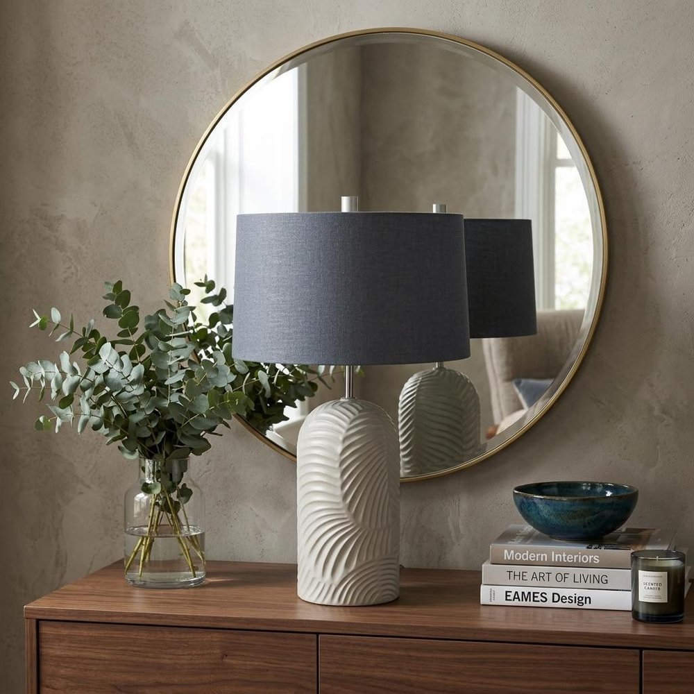 29" Beige Round Bedside Lamp With Drum Shade styled in a furnished interior with a tan wall on a dark wood floor.