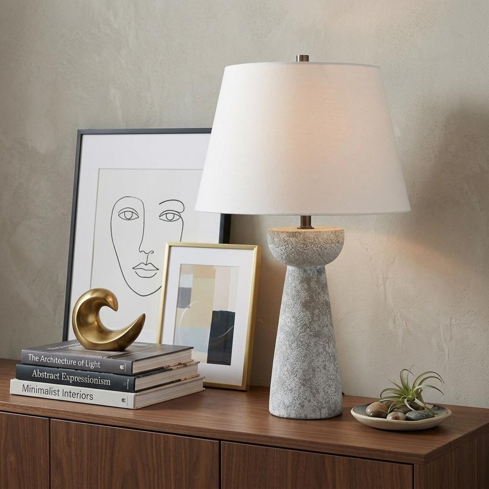 27" Gray Round Bedside Lamp With Empire Shade styled in a furnished interior with a light gray wall on a dark wood floor.
