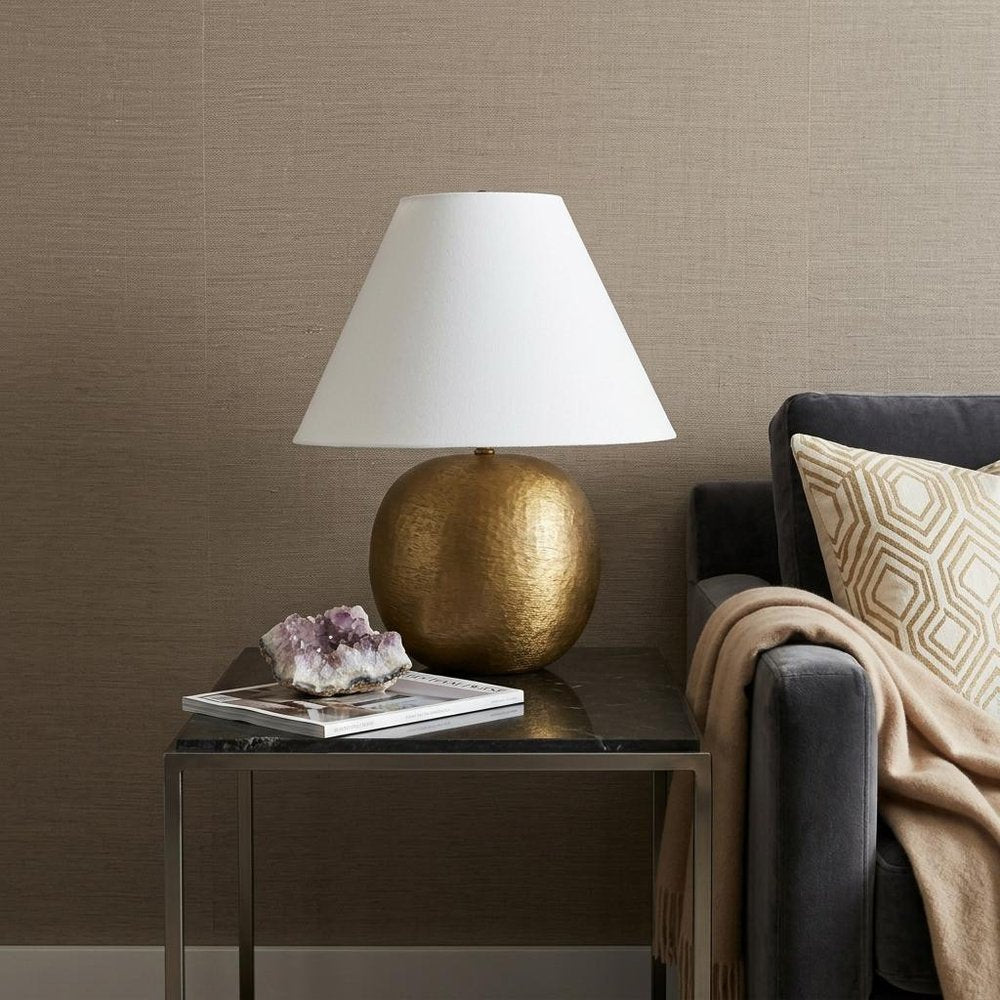 24" Gold Round Bedside Lamp With Empire Shade styled in a furnished interior with a tan wall on a dark wood floor.