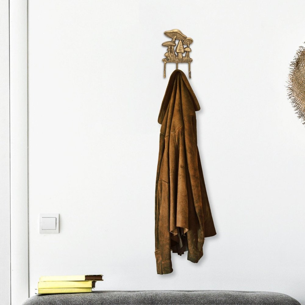 5" Antiqued Gold Cast Iron Mushroom Three Hook Wall Mount Coat Rack. Coat hanger isolated on a plain white background, showing a metal surface.