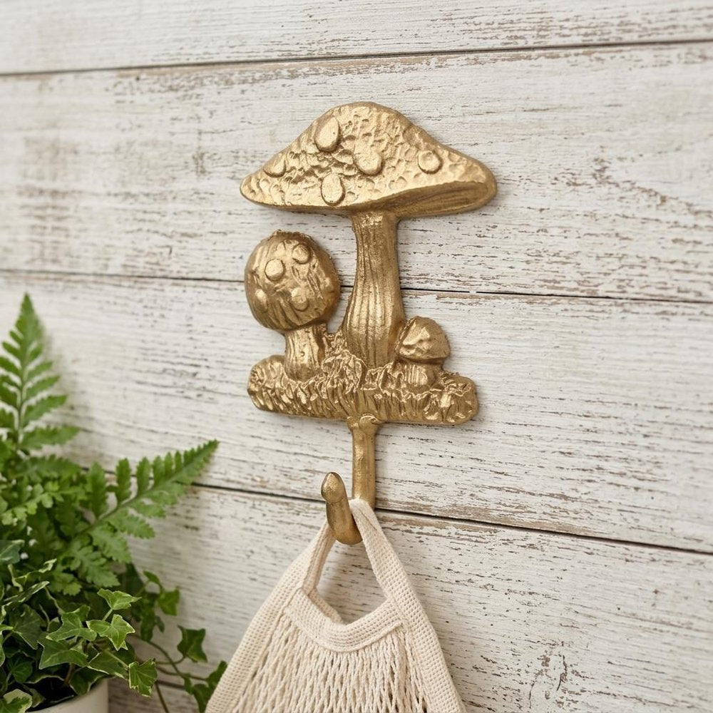 4" Gold Cast Iron Mushroom Wall Hook styled in a furnished interior with an off-white wall on a tiled floor.