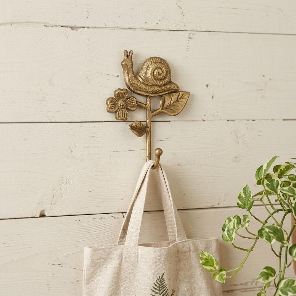 5" Gold Cast Iron Snail Wall Hook styled in a furnished interior with a cream wall on the floor.