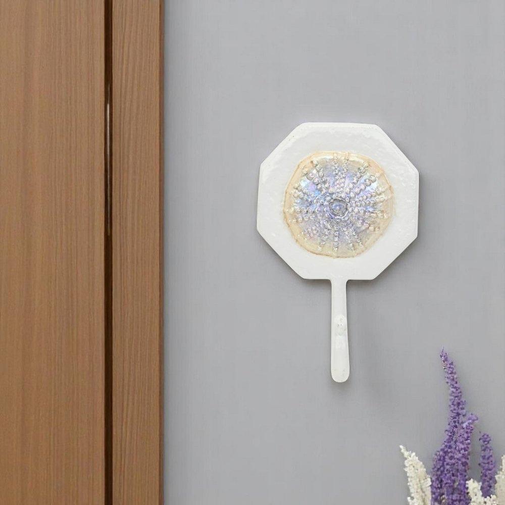 4" Pearl And White Cast Iron Sand Dollar Wall Hook styled in a furnished interior with a light gray wall on a tiled floor.
