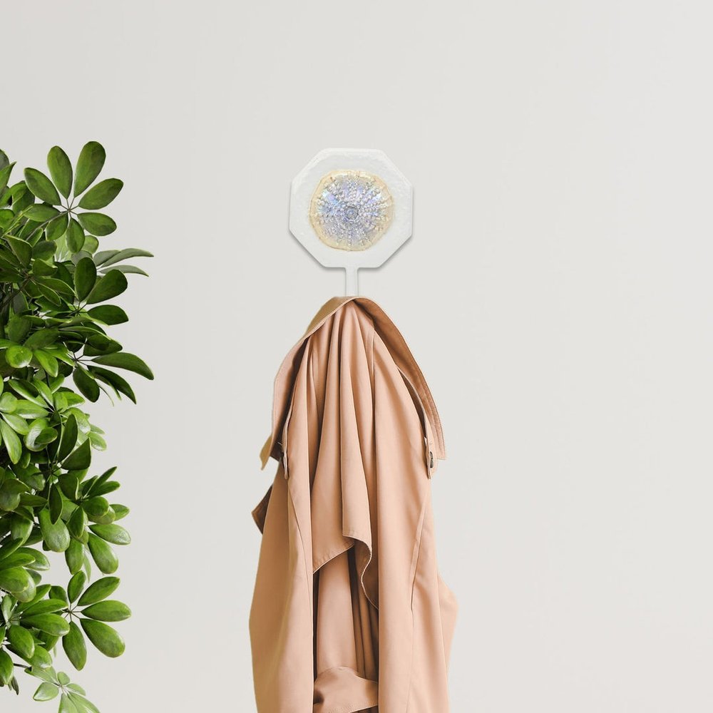 4" Pearl And White Cast Iron Sand Dollar Wall Hook shown outdoors on an outdoor setting with greenery.