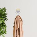 4" Cream And Pearl Cast Iron Seashell Wall Hook shown outdoors on an outdoor setting with greenery.