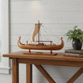 13" Unfinished Wood Hand Painted Model Boat styled in a furnished interior with a light gray wall on a tiled floor in light gray wood.