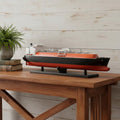 10" Unfinished Wood Hand Painted Model Boat styled in a furnished interior with a light gray wall on a dark wood floor in dark brown wood.