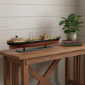 10" Unfinished Wood Hand Painted Model Boat styled in a furnished interior with a light gray wall on a dark wood floor in dark brown wood.