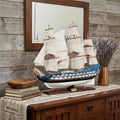 23" Unfinished Wood Hand Painted Boat Model Boat styled in a furnished interior with a tan wall on a dark wood floor in dark brown wood.