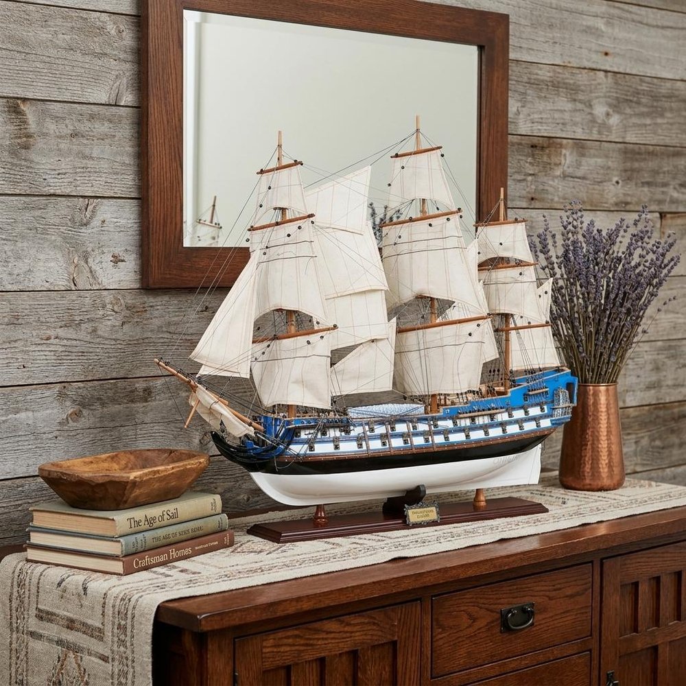 23" Unfinished Wood Hand Painted Boat Model Boat styled in a furnished interior with a tan wall on a dark wood floor in dark brown wood.