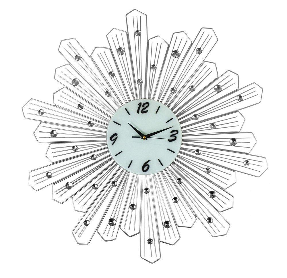 Silver and white metal sunburst wall clock with clear crystals on a white background.