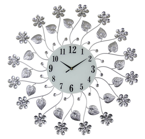 Silver and white metal and glass floral wall clock with black numbers and hands on a white background.
