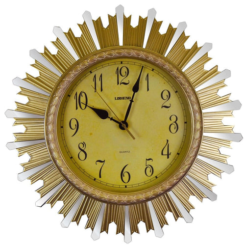 Gold and silver sunburst analog wall clock with a yellow face and black hands, set against a white background.