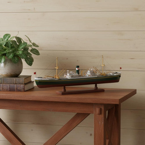 Model ship on a wooden table with a plant and books, against a wood-paneled wall.