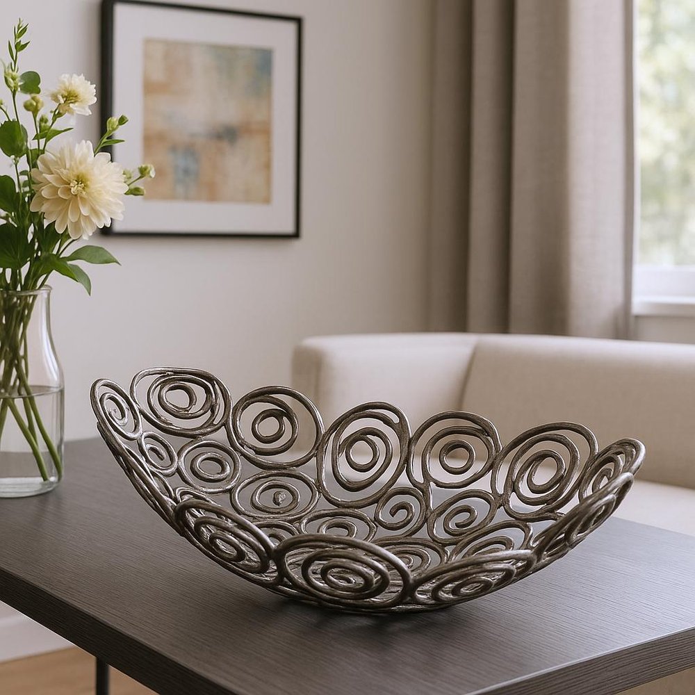 20" Silver Aluminum Abstract Circles Oval Decorative Bowl styled in a furnished interior with a light gray wall on a charcoal floor.