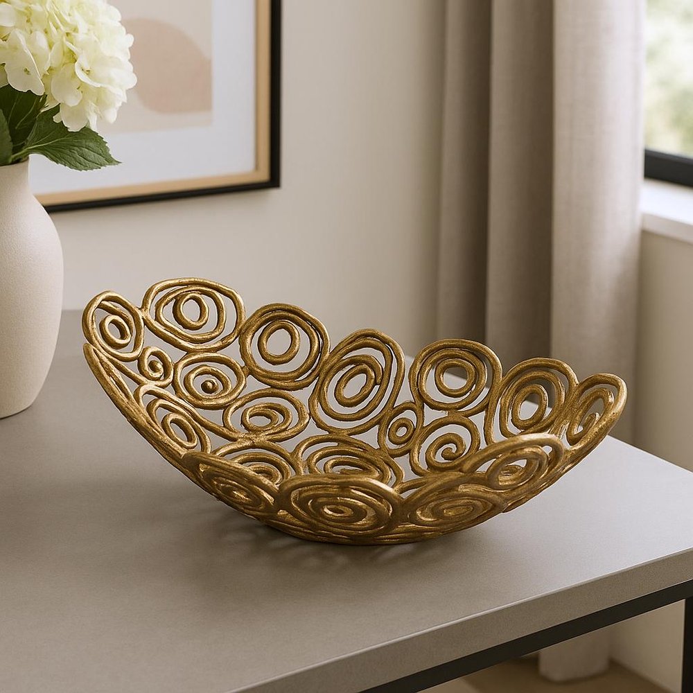 20" Gold Aluminum Abstract Circles Oval Decorative Bowl styled in a furnished interior with a tan wall on a wood floor.