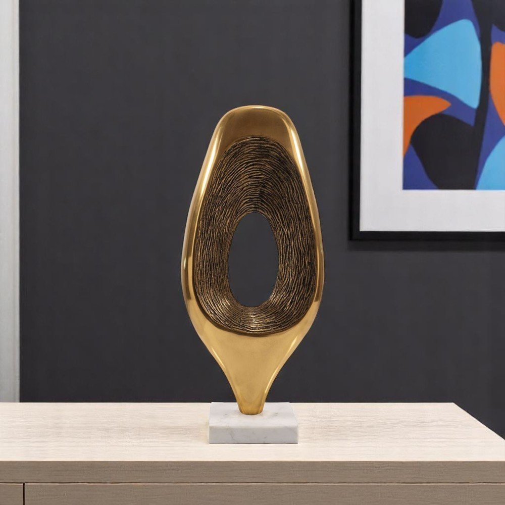 19" Gold And White Aluminum And Marble Abstract Tabletop Sculpture styled in a furnished interior with a dark wall on a off-white floor.