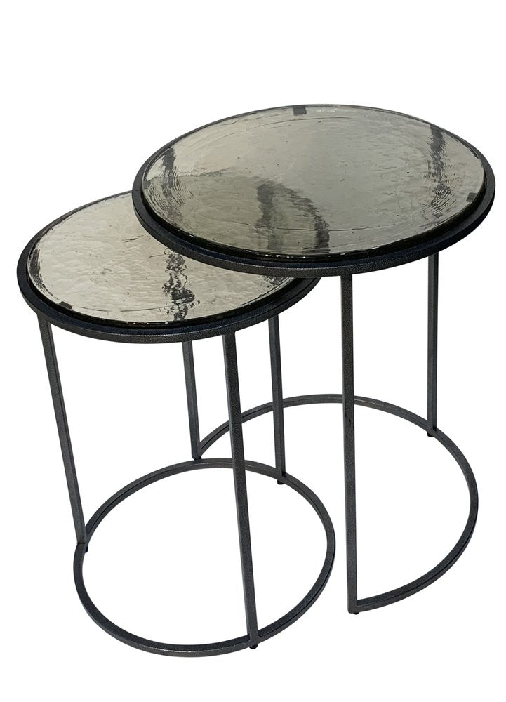 Set of two nesting round tables with textured clear glass tops and gunmetal iron frames on a white background.