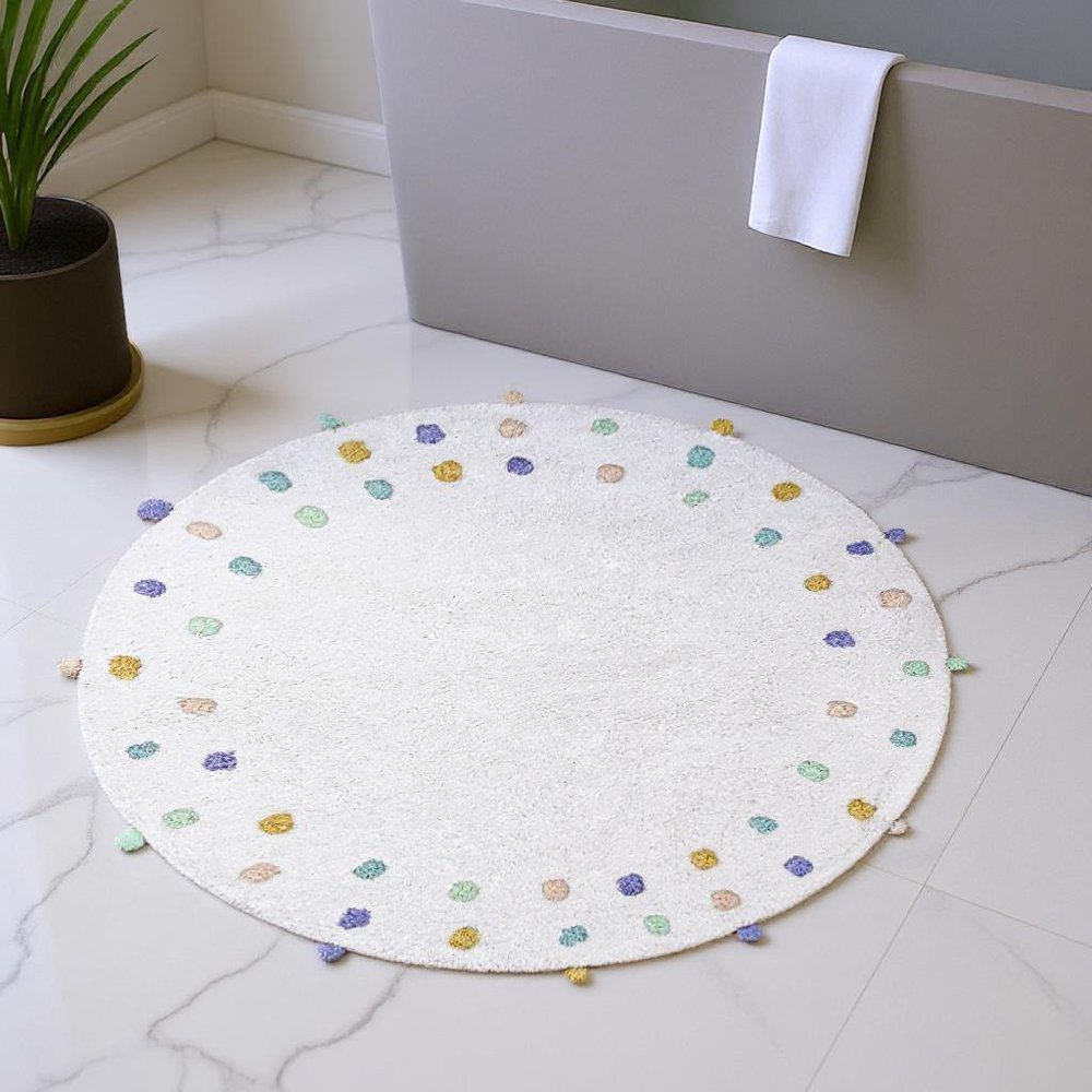 32" Green Purple And White Cotton Round Polka Dots Bath Rug laid on a off-white floor in a furnished interior.