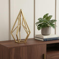 10" Gold Metal Open Geometric Tabletop Sculpture styled in a furnished interior with an off-white wall on a dark wood floor.