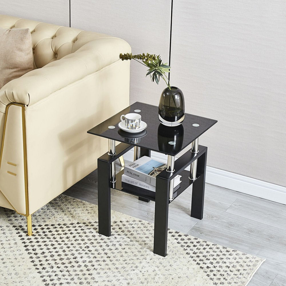 Black glass and steel square end table with shelf next to a cream sofa on a patterned rug.