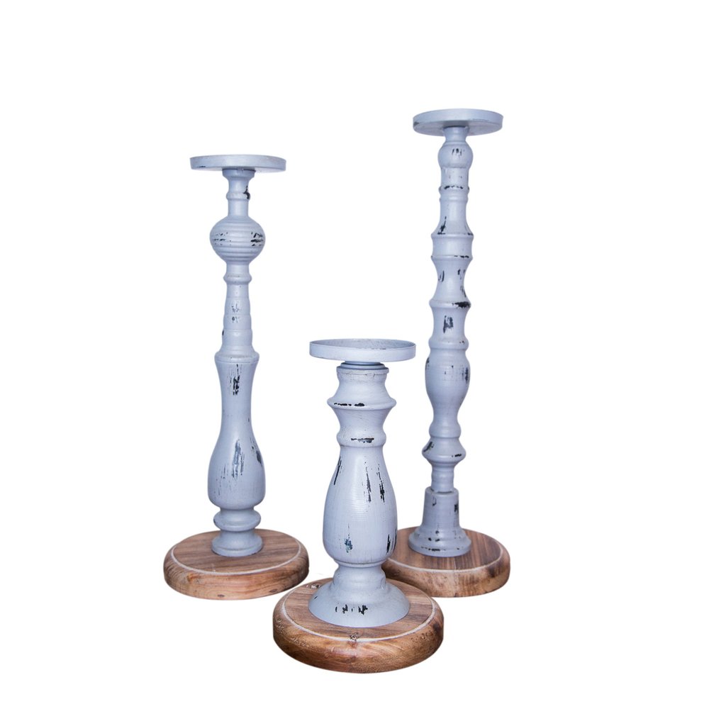 Three distressed gray wood pillar candle holders with natural wood bases on a white background.
